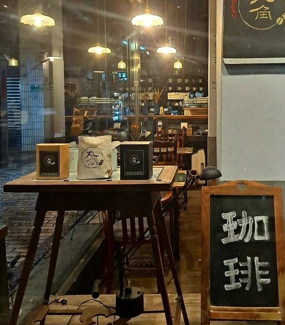 丸角自轉生活咖啡 木桌上的自家品牌咖啡與「珈琲」黑板窗景